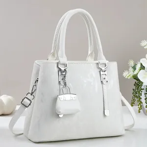 Detail of white tote bag featuring vertical embossed texture and silver metal hardware