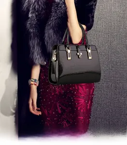 Detail of crocodile pattern black patent leather handbag with gold hardware and top handles