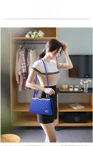 Détail de la texture matelassée bleu vif et du nœud doré sur un sac à main tendance