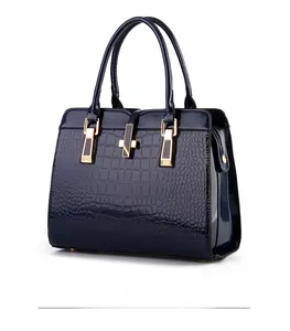 Detail of navy blue crocodile pattern patent leather handbag with metal buckle and dual handles