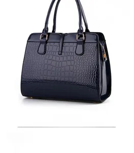 Detail view of deep blue crocodile embossed patent leather with gold metal hardware