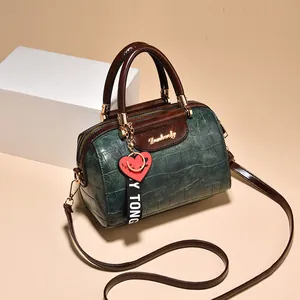 Bolso boston retro verde oscuro con relieve de cocodrilo y asas marrones en contraste