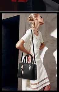 Détail d'un sac à main en cuir noir avec pendentif chat doré et pompons élégants