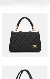Détail du sac bandoulière matelassé noir avec nœud doré et poignée métallique