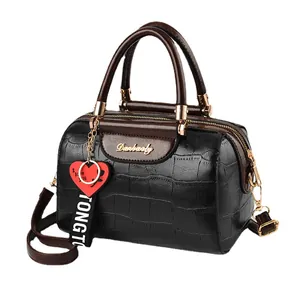 Bolso boston negro con relieve de cocodrilo, asas marrones y colgante de corazón rojo