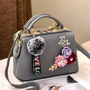 Graue Lederhandtasche mit Blumenstickerei und goldenem Metallverschluss in 45-Grad-Ansicht