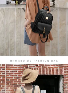 Detail of black quilted backpack with gold hardware and tassel on leather texture
