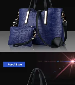 Close-up of royal blue crocodile embossed tote bag with gold metal details and matching pouch
