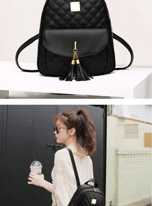 Detail of black quilted leather backpack featuring gold hardware and stylish dual tassels