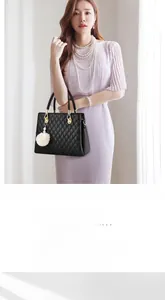 Detail of black quilted handbag with elegant gold hardware and a white fur ball pendant