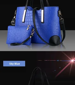 Detail of sky blue crocodile embossed tote bag set with black handles and metal hardware