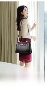Detail of elegant black handbag with burgundy flap and polished gold-tone hardware