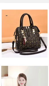 Détail d'un sac cabas marron avec monogramme DIAL, dorure et pendentif chat élégant