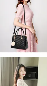 Quilted black leather handbag featuring gold hardware and a fluffy white pom pom charm