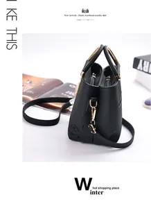 Detalle de bolso en cuero negro con rosa grabada y asa de anillo metálico dorado