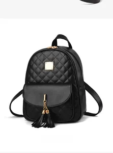 Detail of black quilted backpack with gold metal plaque and double tassel decor