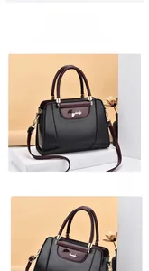 Detail showing elegant black PU leather handbag with wine red handle and golden hardware