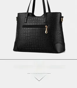 Detail view of black crocodile pattern leather handbag with gold metal zipper and handles