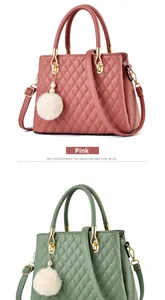 Close-up of quilted handbag texture with pom-pom charm and golden hardware detail