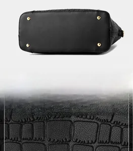 Detail of black crocodile texture leather and golden protective bottom studs on the handbag