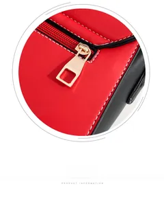 Detail of red and black PU leather crossbody bag featuring white stitching and gold zipper