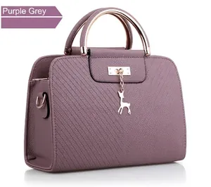 Detail of purple grey handbag with wavy texture, metal handle and gold deer charm
