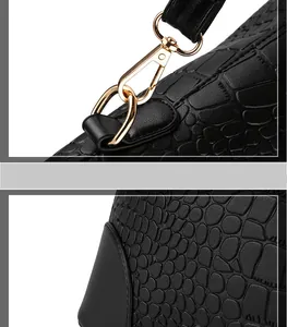 Detail of crocodile embossed leather texture and gold metal hardware on women's handbag
