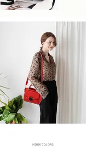Red lychee grain handbag with black circular buckle shown on model with leopard shirt