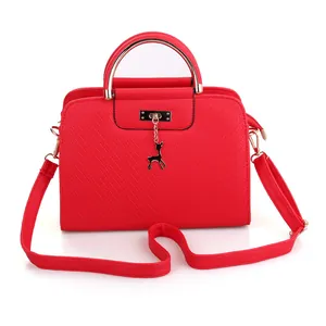Detail of red quilted handbag with gold metal handle and deer pendant charm decoration