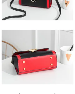 Detail view of red and black PU crossbody bag showing gold feet and white stitching
