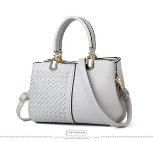 Detail der grauen Handtasche mit Webstruktur, drei Fächern und goldfarbenen Beschlägen