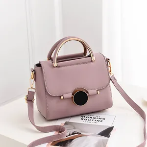 Lavender faux leather handbag with circular clasp and gold circular handle shown in profile