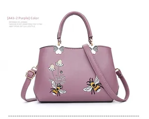 Detail der lila Ledertasche mit Bienen- und Gänseblümchen-Stickerei und Goldbeschlägen