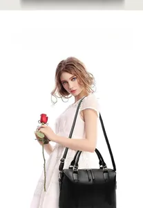 Détail du sac Boston noir en cuir avec fermetures dorées et bandoulière ajustable