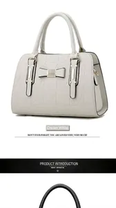 Close-up of off-white handbag featuring geometric quilting and metal bow detail