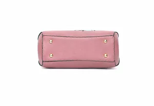 Detalle de bolso rosa con cuatro pies de metal dorado y bordes negros pintados