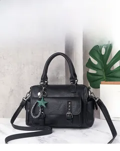 Detail of black Boston bag with metallic rivets, star pendant and adjustable strap