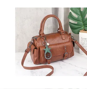 Close-up of brown PU leather Boston bag with star charm and silver rivet details