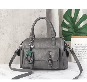 Detail of grey pebble leather Boston bag with green star charm and side pockets