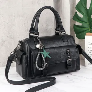 Black Boston handbag with lychee pattern, rivet pocket and stylish charm on grey background