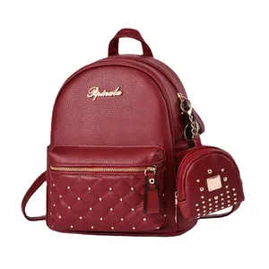 Red quilted leather backpack with gold studs and a matching coin purse on plain background