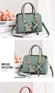 Close-up of green handbag with flower embroidery and a leather butterfly pendant