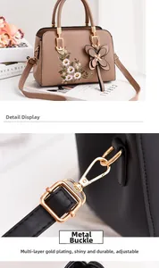 Detail of adjustable strap with gold-plated hardware and buckle on black leather bag