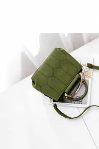 Detail of olive green quilted bag with hexagonal stitching and gold circular handles