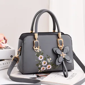 Elegant grey crossbody bag featuring floral embroidery and butterfly pendant for women