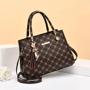 Sac cabas marron à imprimé floral avec gland et breloque chat argentée sur socle blanc