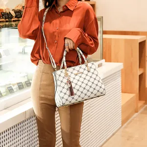 Sac à main blanc élégant avec motif losanges sombres, pompons et boucles dorées chic en vue