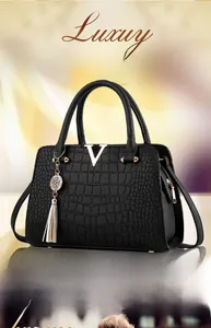Close-up of black crocodile texture handbag with gold metal V-logo and tassel detail