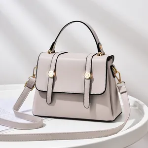 Minimalist beige crossbody small square bag with top handle and gold hardware detail