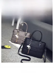 Detail of PU leather tote with striped weave texture, gold cat charm, and tassels